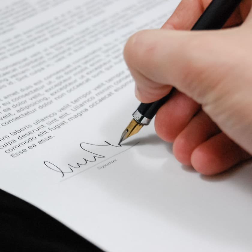 Mão assinando um documento com caneta-tinteiro